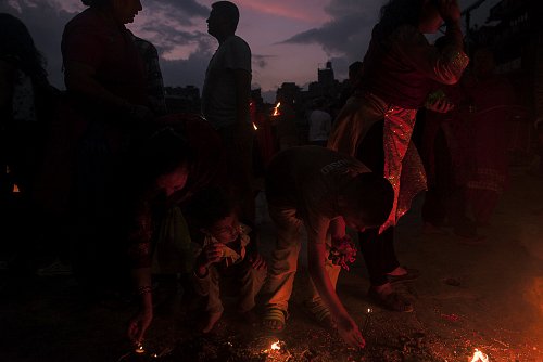 Mick Stetson - As twilight sweeps the city of Bhaktapur, throngs of worshipers sing & chant their way to the temple to pay homage to Durga, the goddess of the victory over evil. Young worshipers avidly take part in lighting holy lamps & circumambulating the day’s designated temple.
